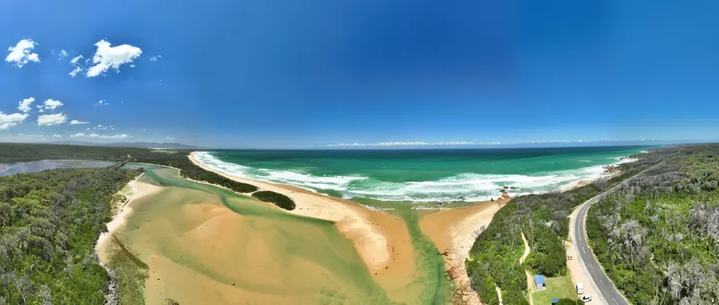 Drone panorama of Betka Beach near Mallacoota, where the river meets the sea between bushland and sand.